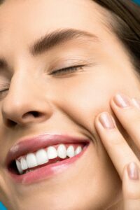 画面いっぱいに笑顔を見せる女性の顔のクローズアップ。白く整った歯と滑らかな肌が印象的で、清潔感と健康的な美しさを表現している。